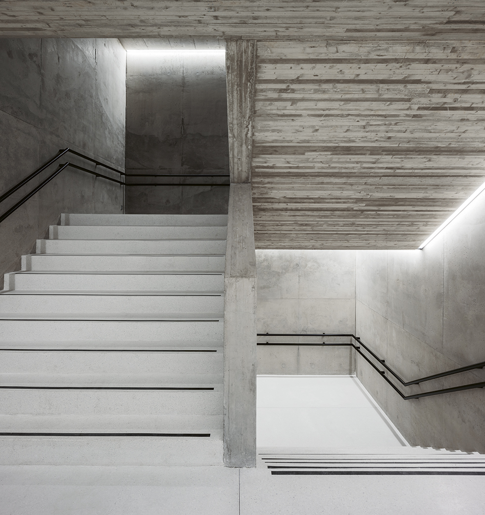 Uusi betoniporras yhdistää aulat maanalaisiin liikuntatiloihin. Seinä- ja porrasvalujen betonia on vaalennettu Semtu Oy:n Titaaninvalkoinen R -titaanioksidilla. Lattiapinnoissa ja porrasaskelmissa on käytetty valkoista, hiottua mosaiikkibetonia. Kuva: Tuomas Uusheimo