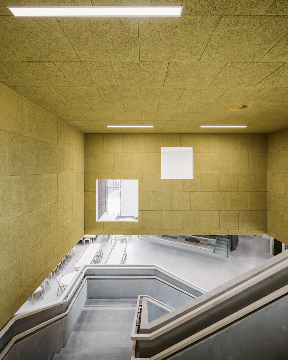 2. kerrokseen johtavasta portaasta avautuvat näkymät monitoimiaulaan- ja auditoriotiloihin. Koulussa on käytetty tehosteena eri värejä. Tiloissa on käytetty akustiikkalevynä palamatonta ja kestävää Paracem- levyä, joka on valmistettu hienohöylätystä kuusilastusta ja sementistä. Kuva: Martin Sommerschield-Kuvio