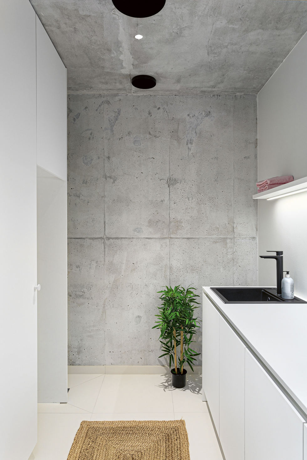 Paikallavaletutu betonipinnat ovat näkyvissä myös kylpyhuone- ja kodinhoitotiloissa.