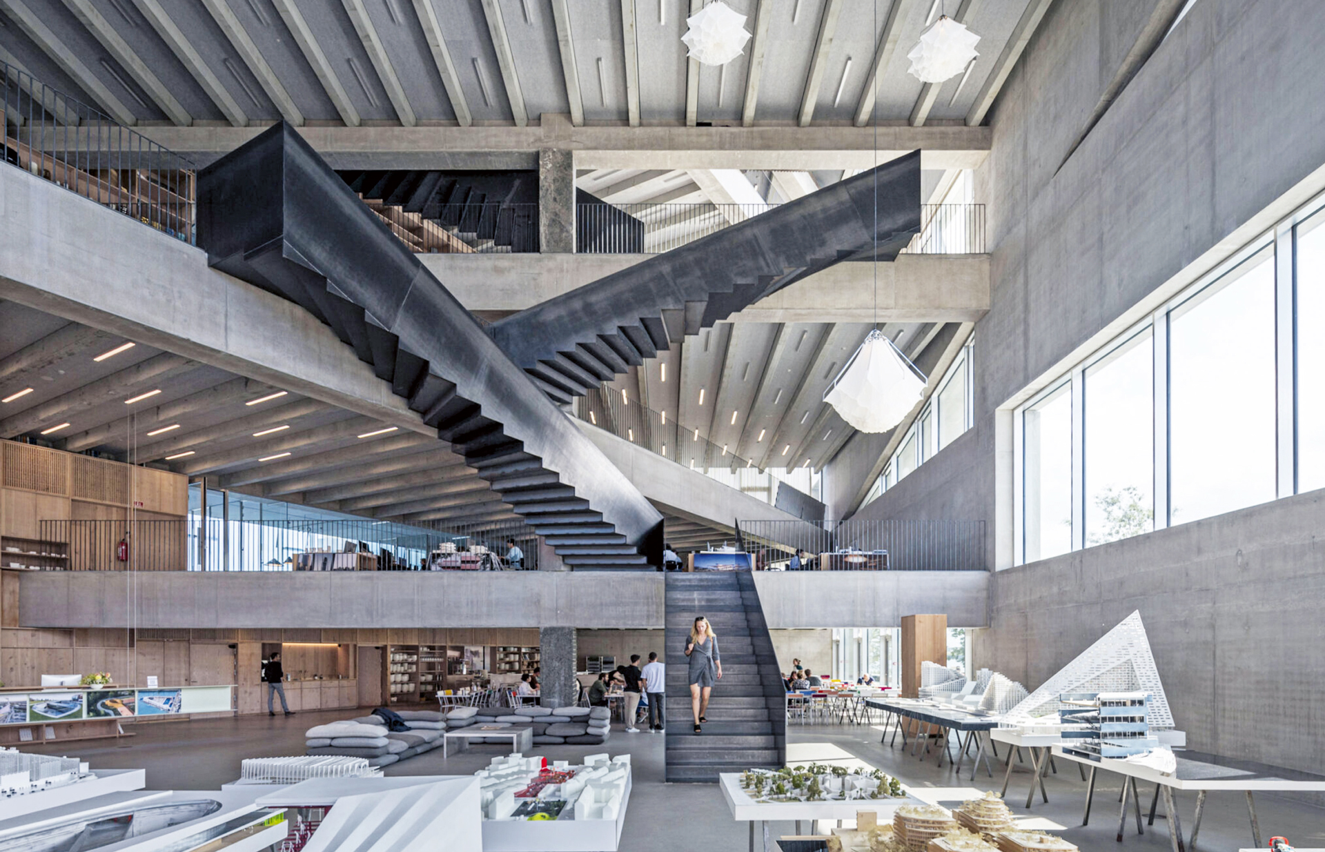 Sisääntulokerroksessa on toimiston suunnittelemien töiden näyttely sekä ruokala. Mustaksi käsitellyt teräsportaat yhdistävät kerrokset toisiinsa. TT-laattojen ripojen välit on on peitetty akustisella EcoSUNDilla. Se on valmistettu 100 prosenttisesta polyesterikuidusta, josta puolet on peräisin kierrätetyistä PET-muovipulloista. Kuva: Rasmus Hjortshøj